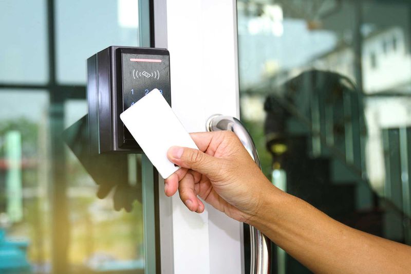 : Close-up hand inserting keycard to lock and unlock door - Door access control keypad with keycard reader. types of access control.